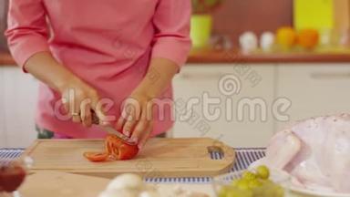在<strong>餐桌</strong>上用健康食品做沙拉的木切割板上切<strong>番茄</strong>肉的特写镜头